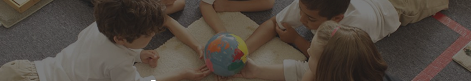 Young children gathered around a globe in a classroom